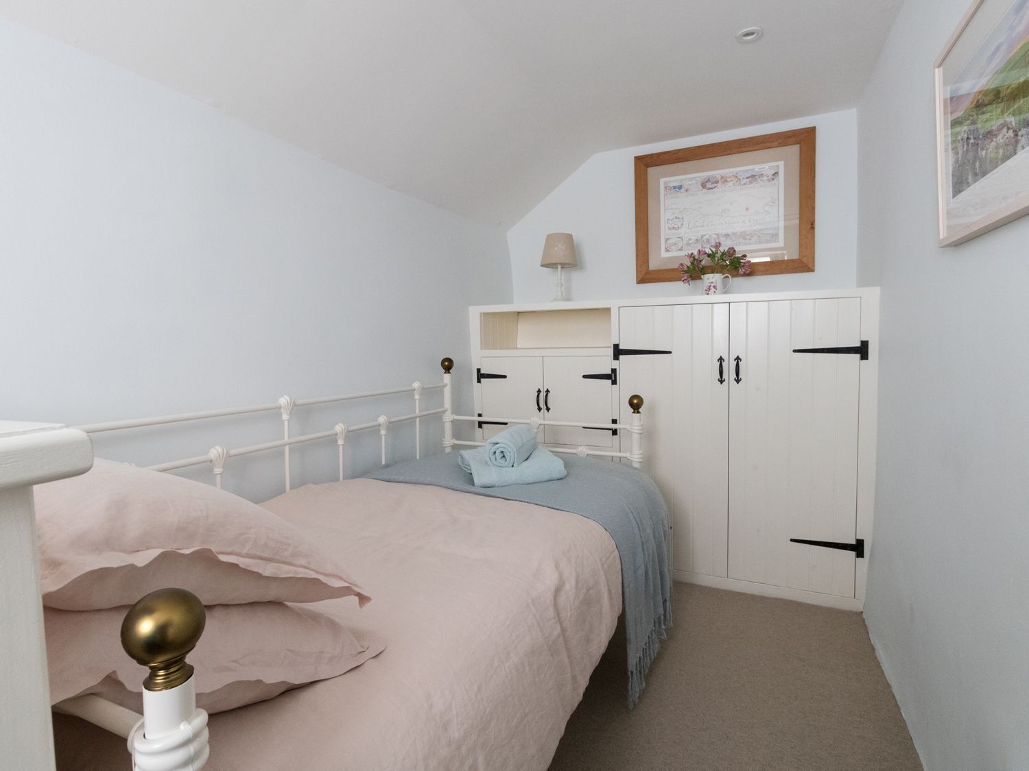 A bedroom with a bed, a wardrobe, and a framed picture on the wall.