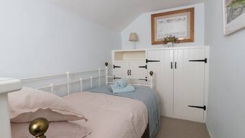 A bedroom with a bed, a wardrobe, and a framed picture on the wall.