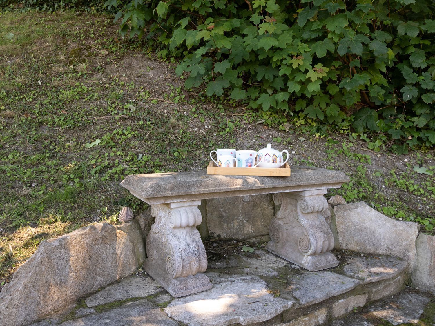 A stone bench with a tray holding a teapot and cups.