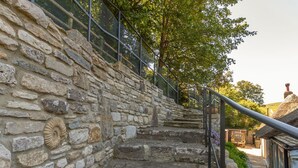 A stone staircase with metal railings, leading to a building with a thatched roof. - Amy Cottage (Wareham)