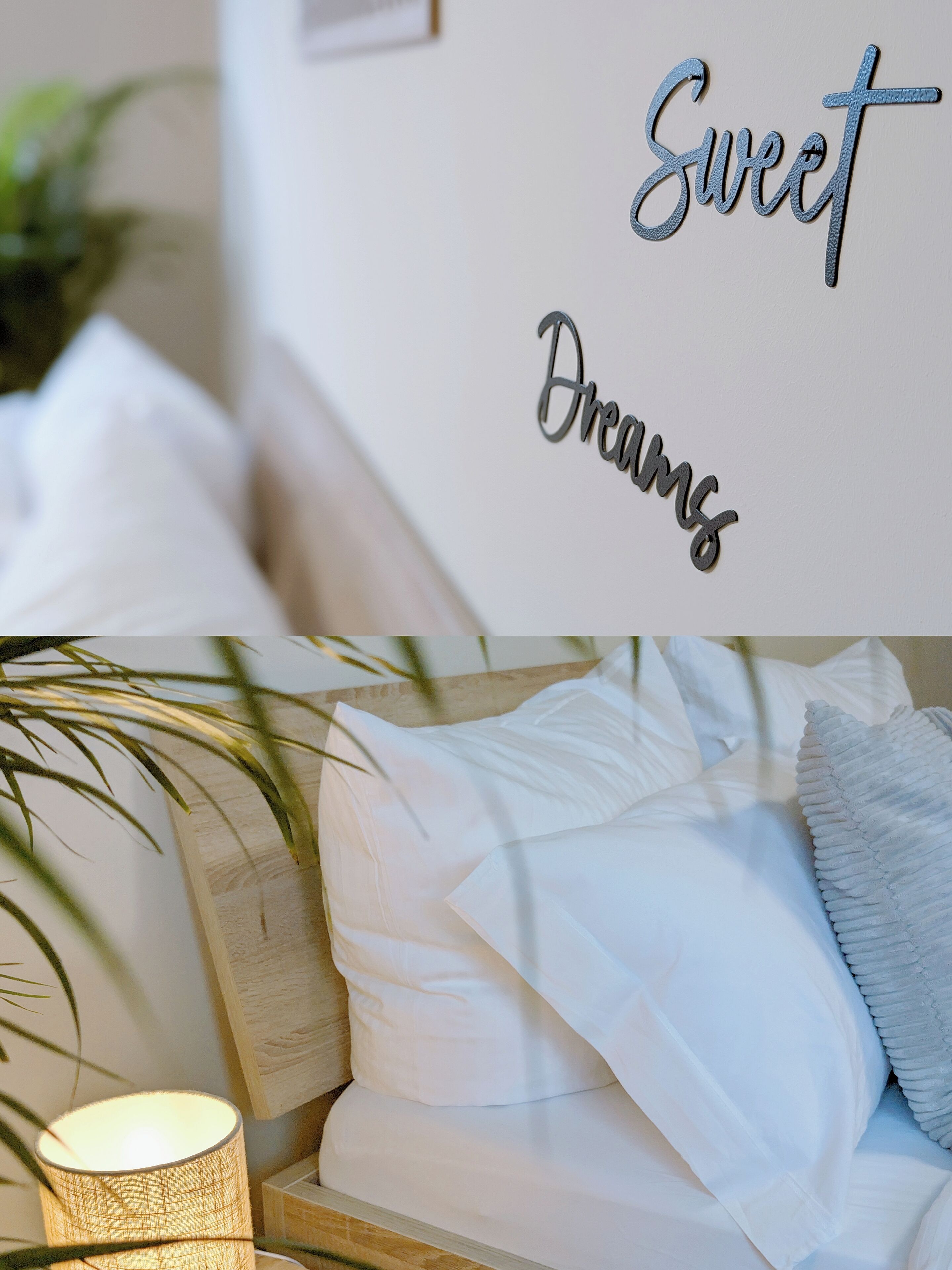 A neatly made bed with white linens and pillows, a wall with the words 'Sweet Dreams' in a decorative font, and a bedside lamp.