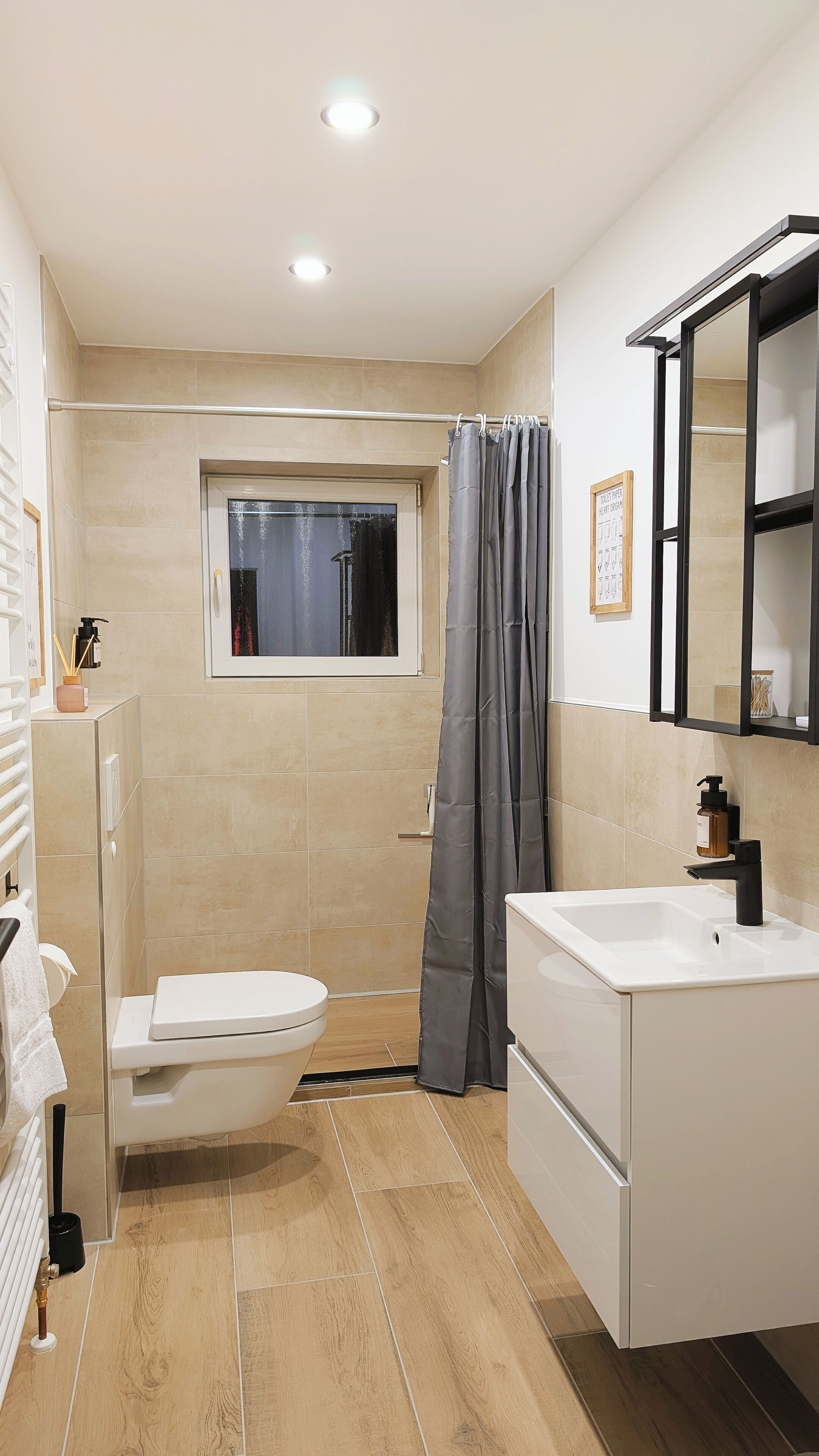 Et moderne badeværelse med toilet, håndvask og bruseområde.