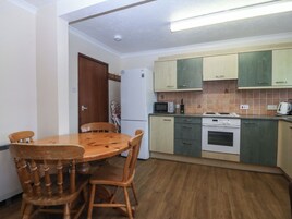 Una cocina compacta con una mesa y sillas, microondas, estufa y armarios.