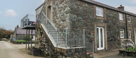 A stone building with a metal staircase leading to a balcony.