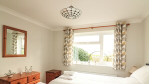 Un dormitorio con dos camas, un tocador, un espejo y una ventana con cortinas.