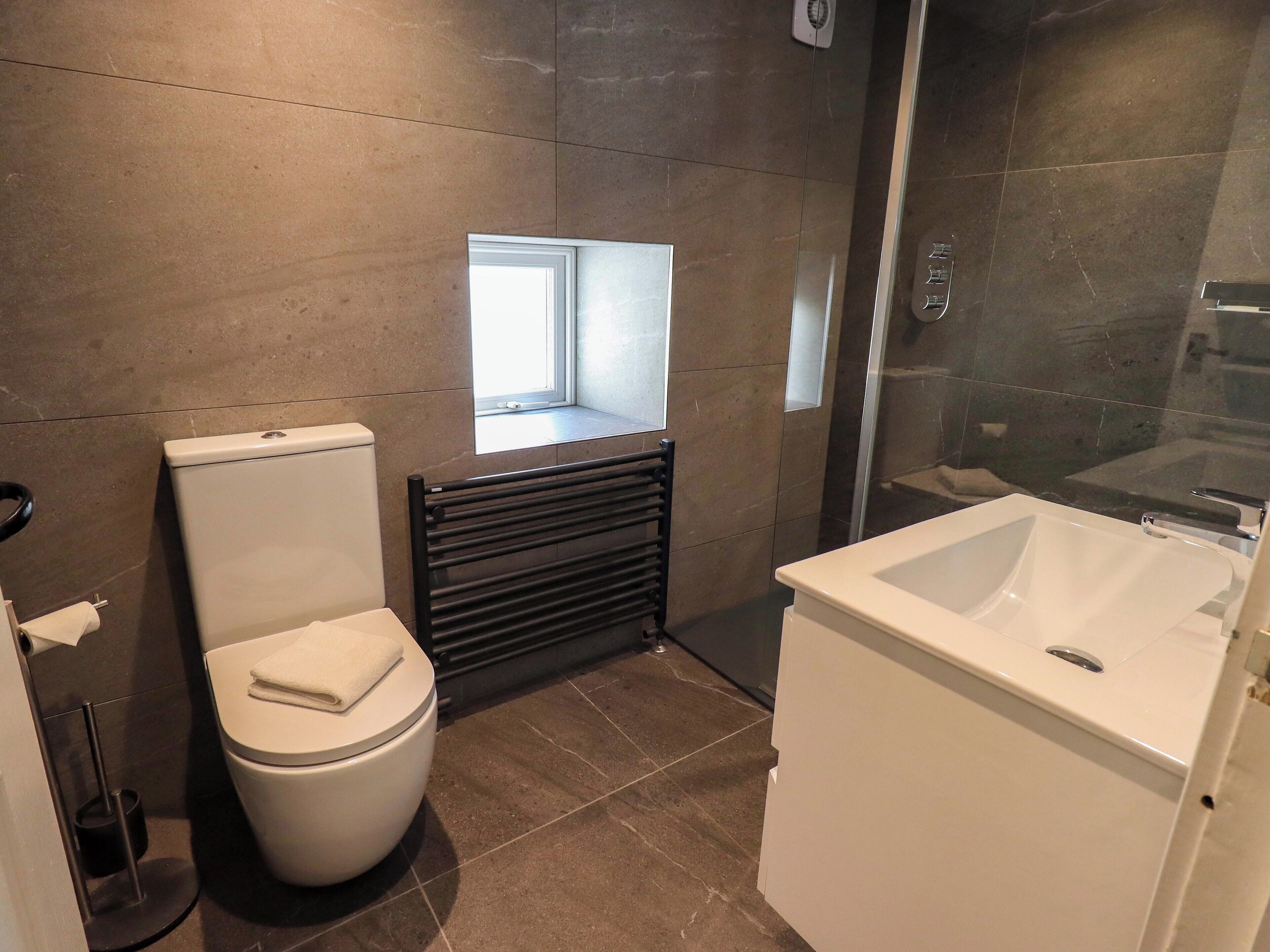 A modern bathroom with a toilet, a shower, and a sink.