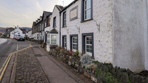 Une rangée de bâtiments blancs aux fenêtres à encadrements sombres, bordant une rue pavée.