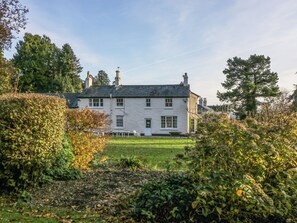 A large white building with multiple chimneys, surrounded by lush greenery and trees. - The Coach House (Abergavenny)