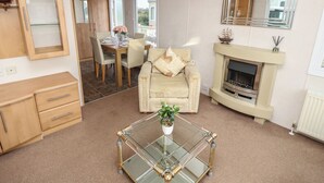 Ein gemütliches Wohnzimmer mit Sofa, Glastisch, Kamin und Essbereich mit Tisch und Stühlen.