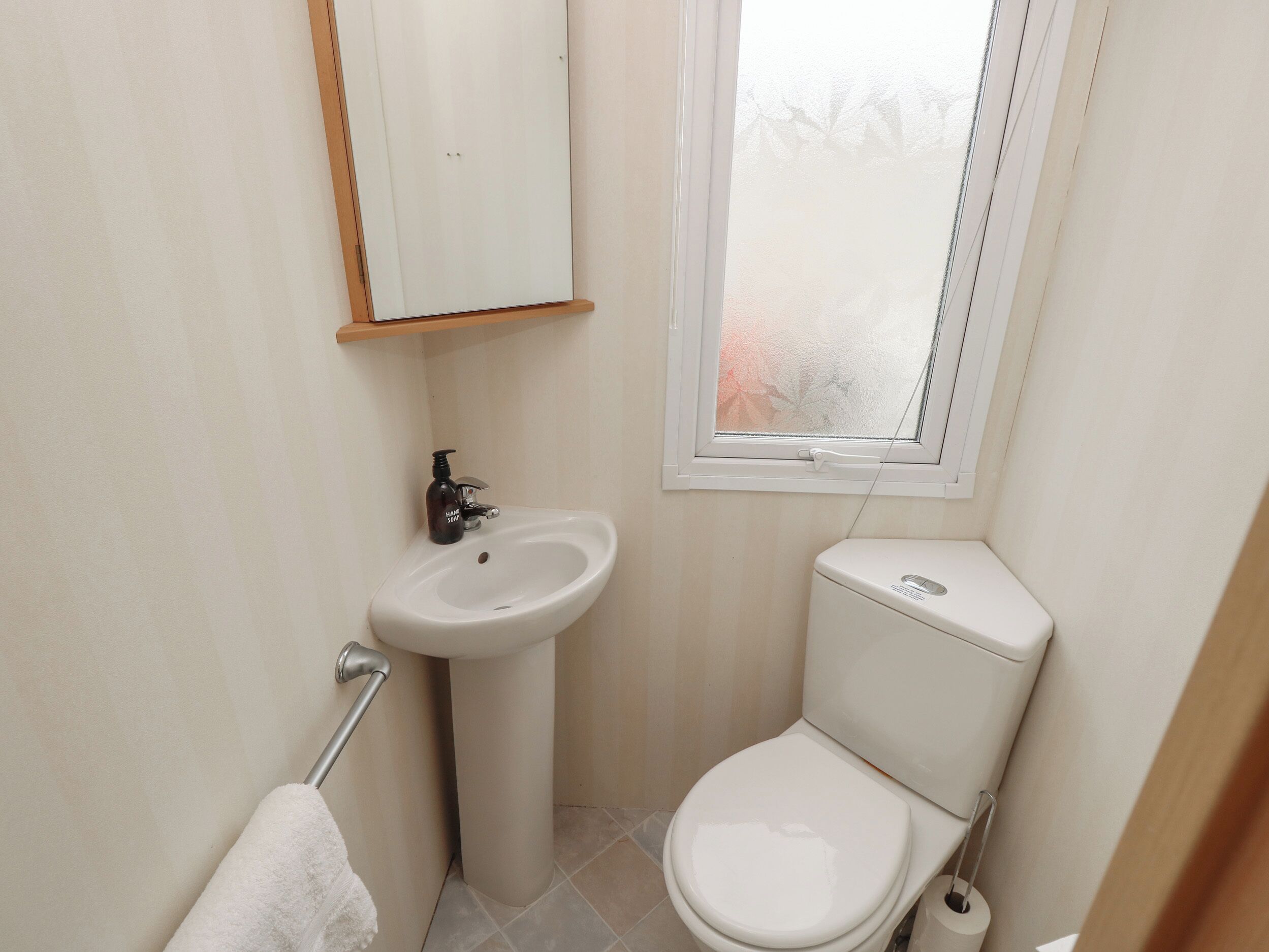 A small, clean bathroom with a toilet, sink, and window.