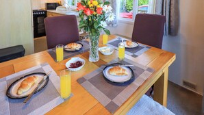 Una mesa de desayuno con croissants, jugo y un florero, en una habitación con vistas al exterior.