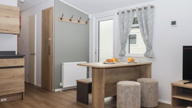 Eine moderne Küche mit Holzausziehtüren, einem Einbauofen und einer Frühstücksecke mit Croissants und Orangensaft.