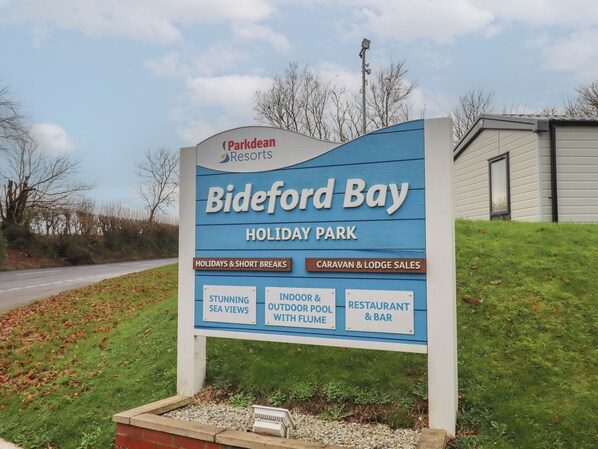 A sign for Bideford Bay Holiday Park, highlighting stunning sea views, indoor and outdoor pool with flume, and a restaurant & bar.