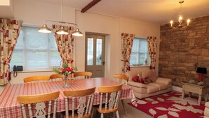 A dining area with a table and chairs, a sofa, and a stone wall. - The Old Post Office (Pickering)