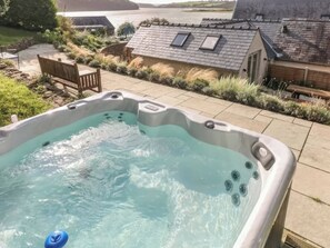 Ein Whirlpool mit Blick auf ein Haus und ein Gewässer im Hintergrund.