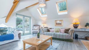 A cozy living room with a wooden table, a sofa, and a patterned rug. - Leeward Cottage (Pembroke)