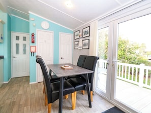 A dining area with a table and chairs, a fire extinguisher, and a door with a white frame. - 3 Bure Close (Great Yarmouth)
