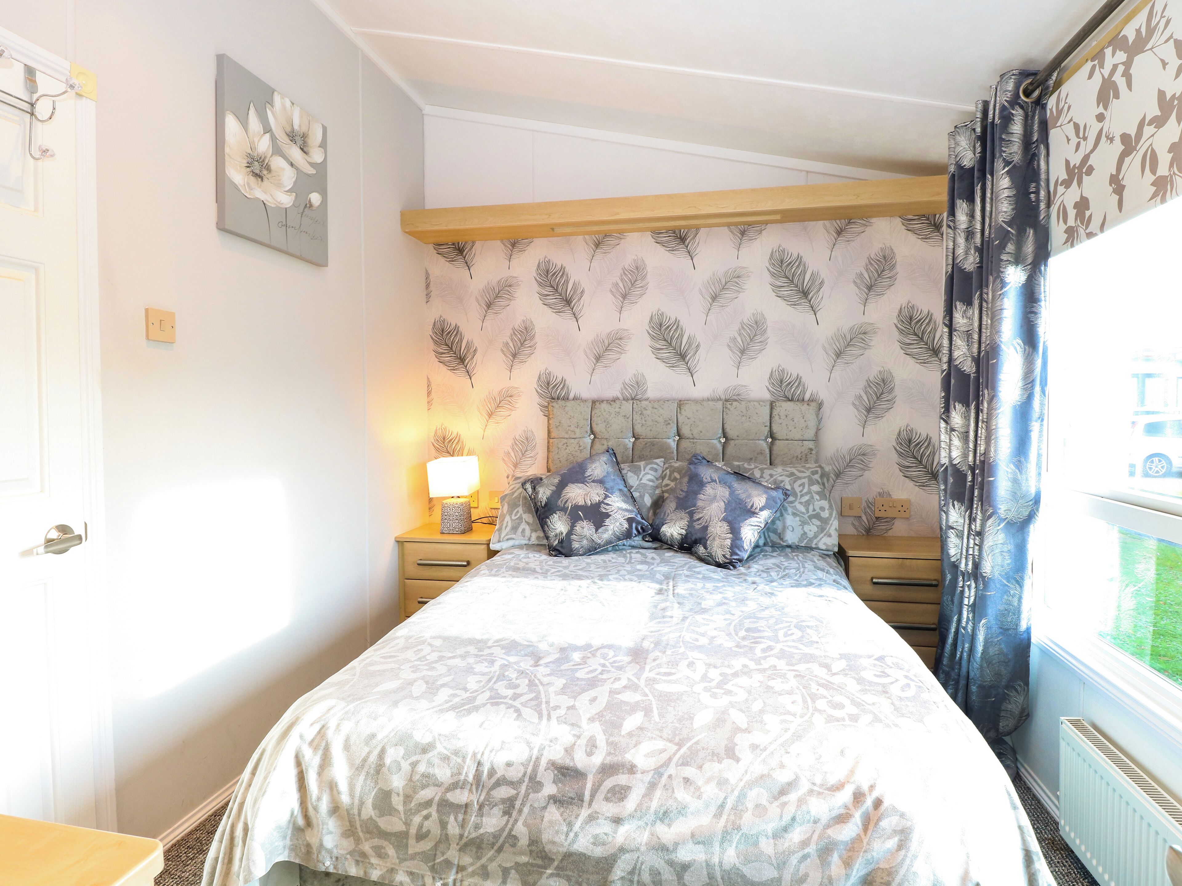 A bedroom with a bed, nightstands, a lamp, and a window with curtains.