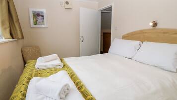 Ein Hotelzimmer mit einem Bett, einem Sessel, einem Gemälde und einer Tür.