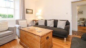 Un salon avec une table basse en bois, deux canapés, un fauteuil et une lampe.