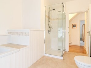 Een moderne badkamer met een douchecabine van glas, een witte badkuip en een toilet.