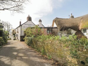 A traditional white building with a sign reading "Journey's End Inn" and a thatched-roof structure nearby. - 3 Cumberland Cottages (Kingsbridge)