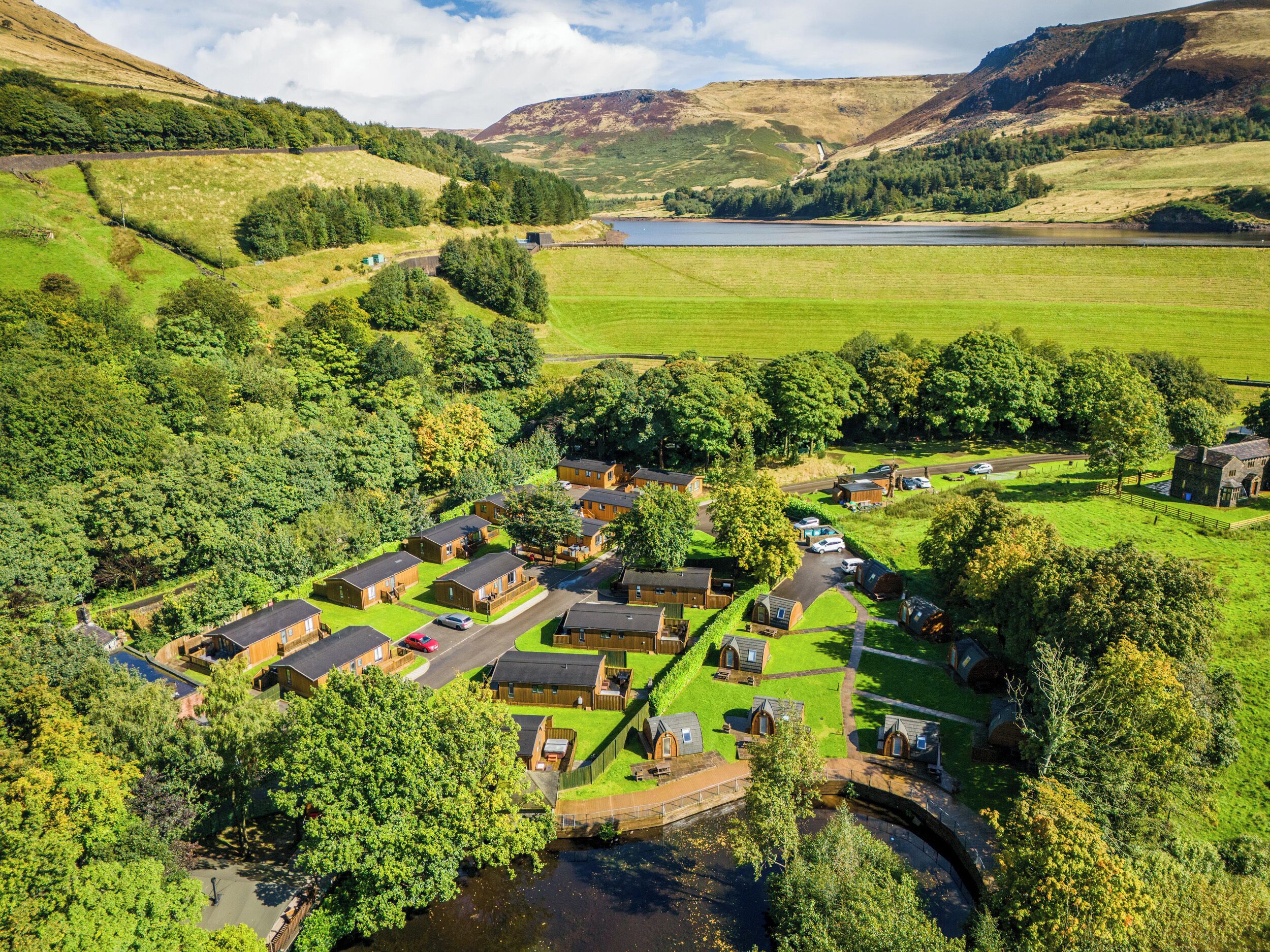 An aerial view of a rural village with cottages, a river, and surrounding hills.