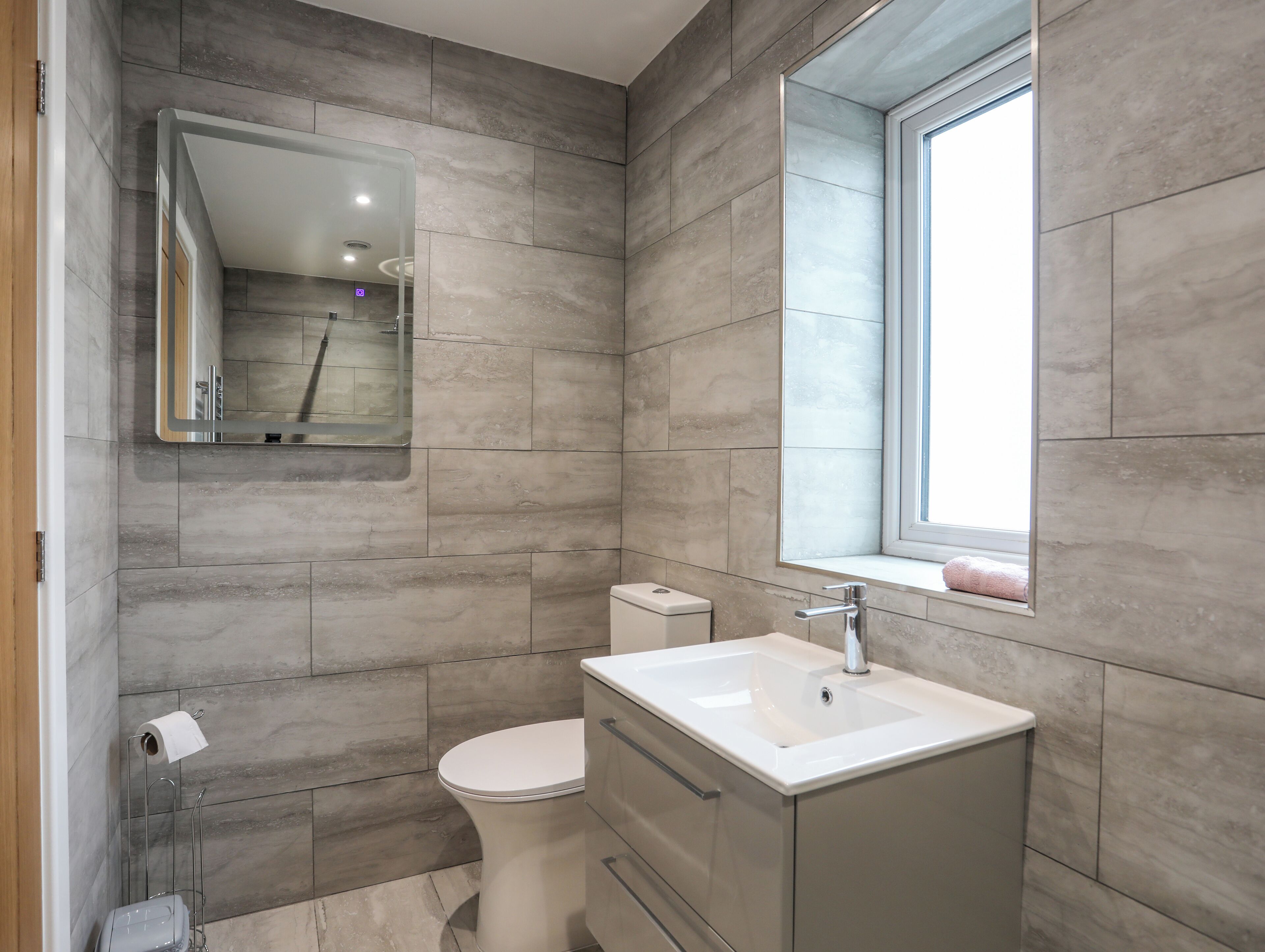 Un baño moderno con inodoro, lavamanos y espejo.
