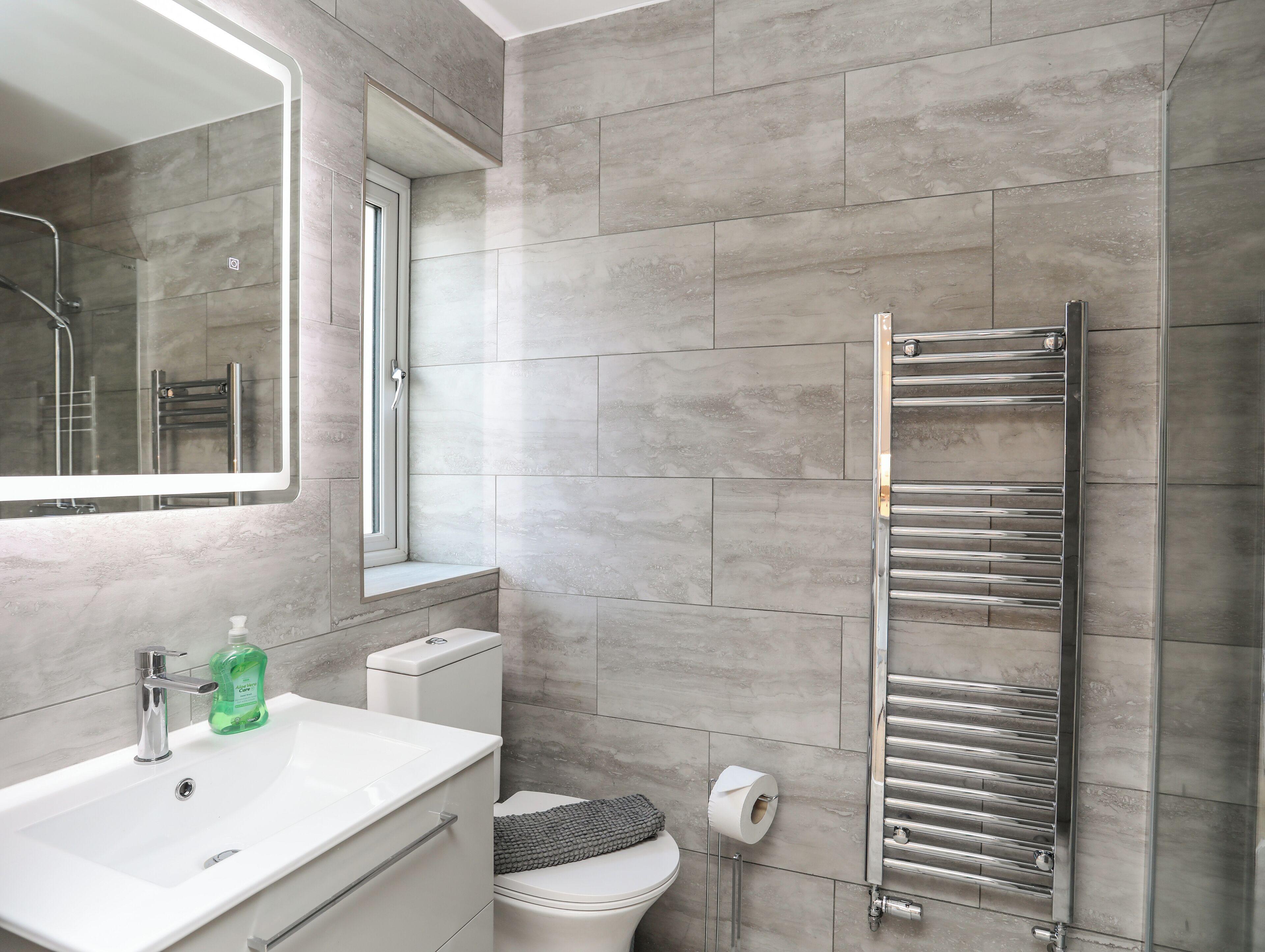 A modern bathroom with a white sink, a mirror, a toilet, and a glass shower enclosure.