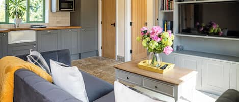 A modern kitchen with grey cabinets, a microwave, and a window with a plant.