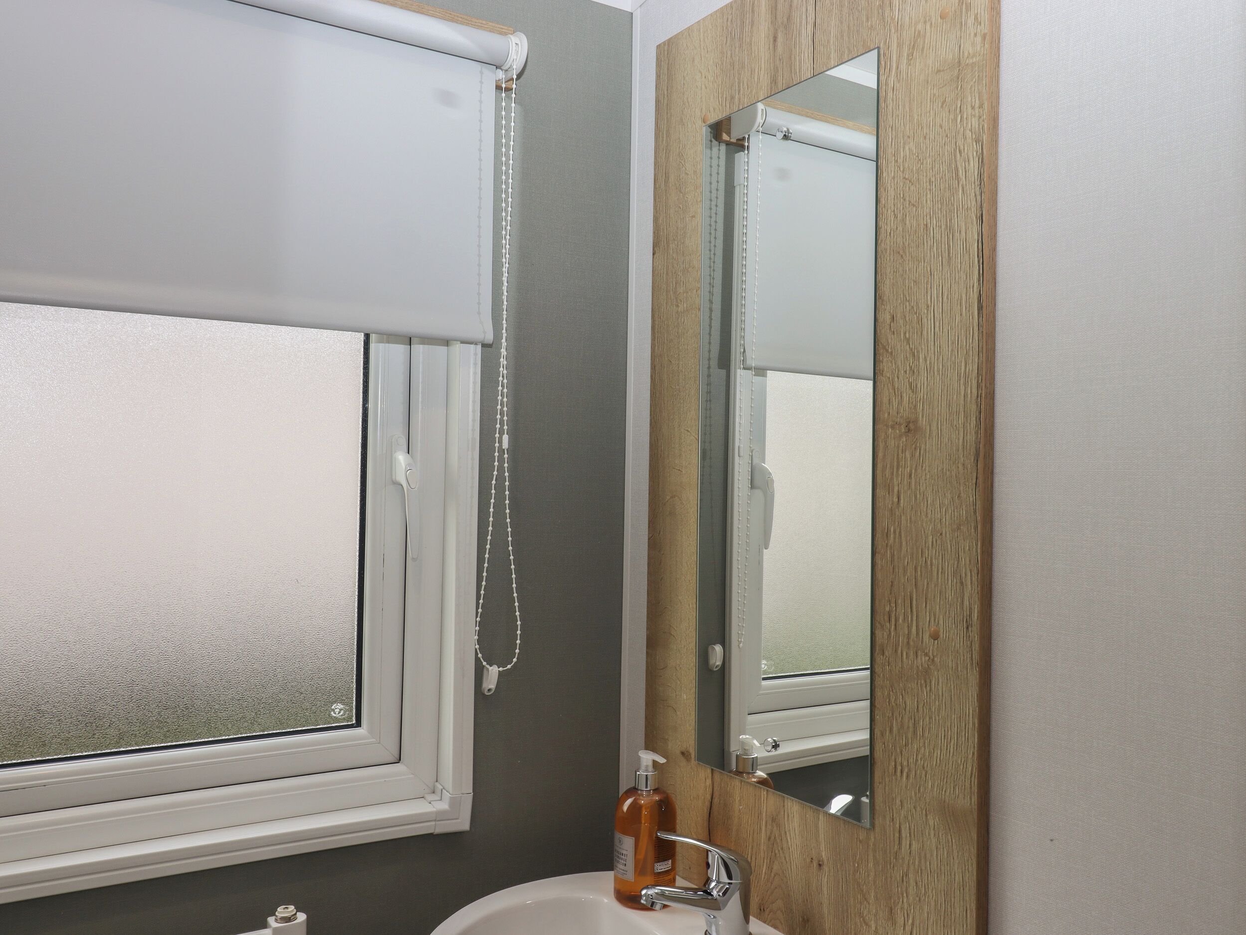 A bathroom with a window, a mirror, and a sink.