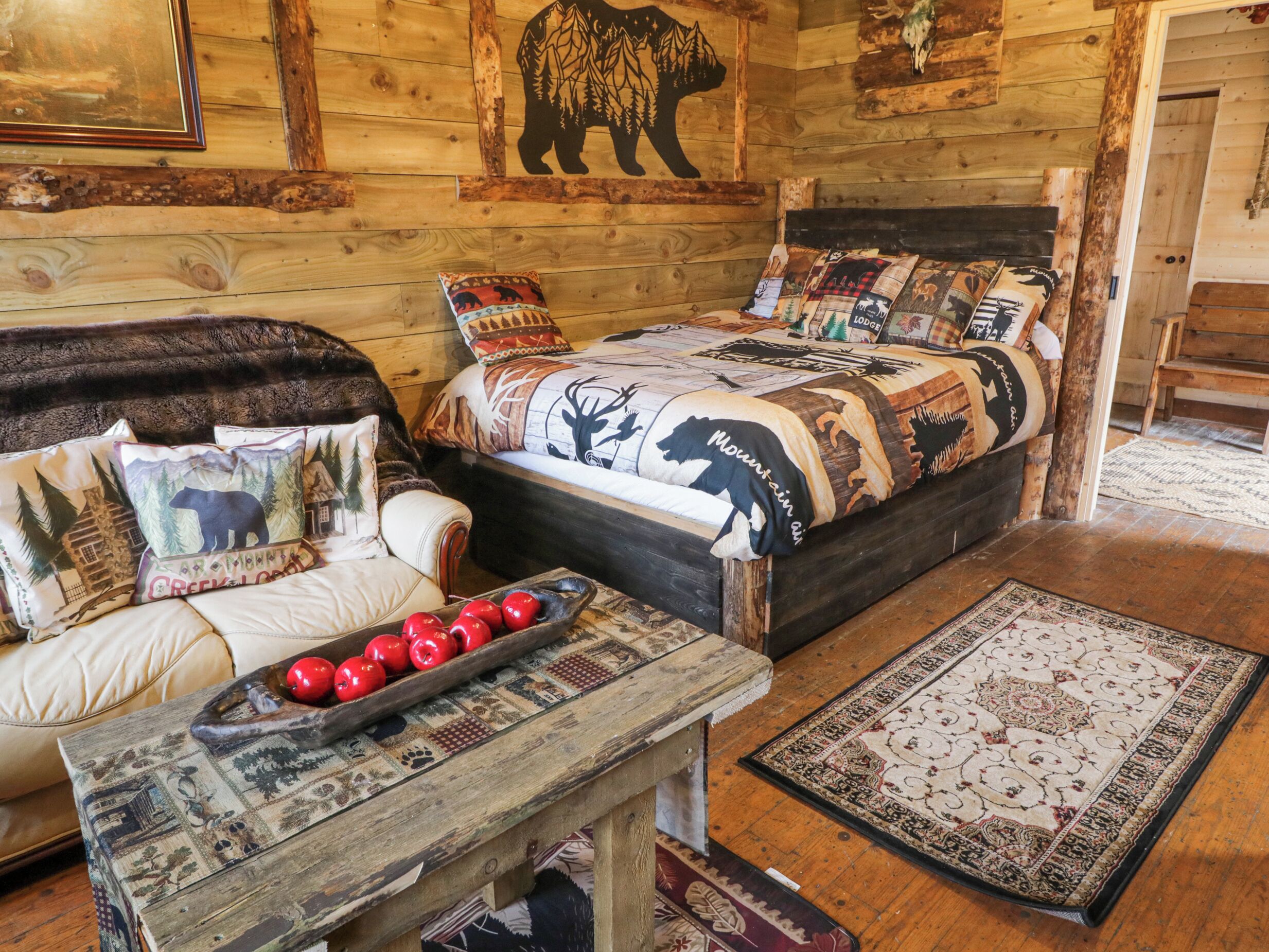 A cozy room with a wooden bed, a sofa, and a table with red apples.