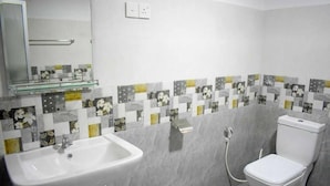 Un baño con lavabo, inodoro y un estante de vidrio sobre el lavabo.