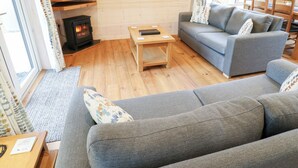 A cozy living room with a sofa, a coffee table, and a fireplace. - Dovestone Secluded Luxury Lodges - Pets Welcome (Oldham)