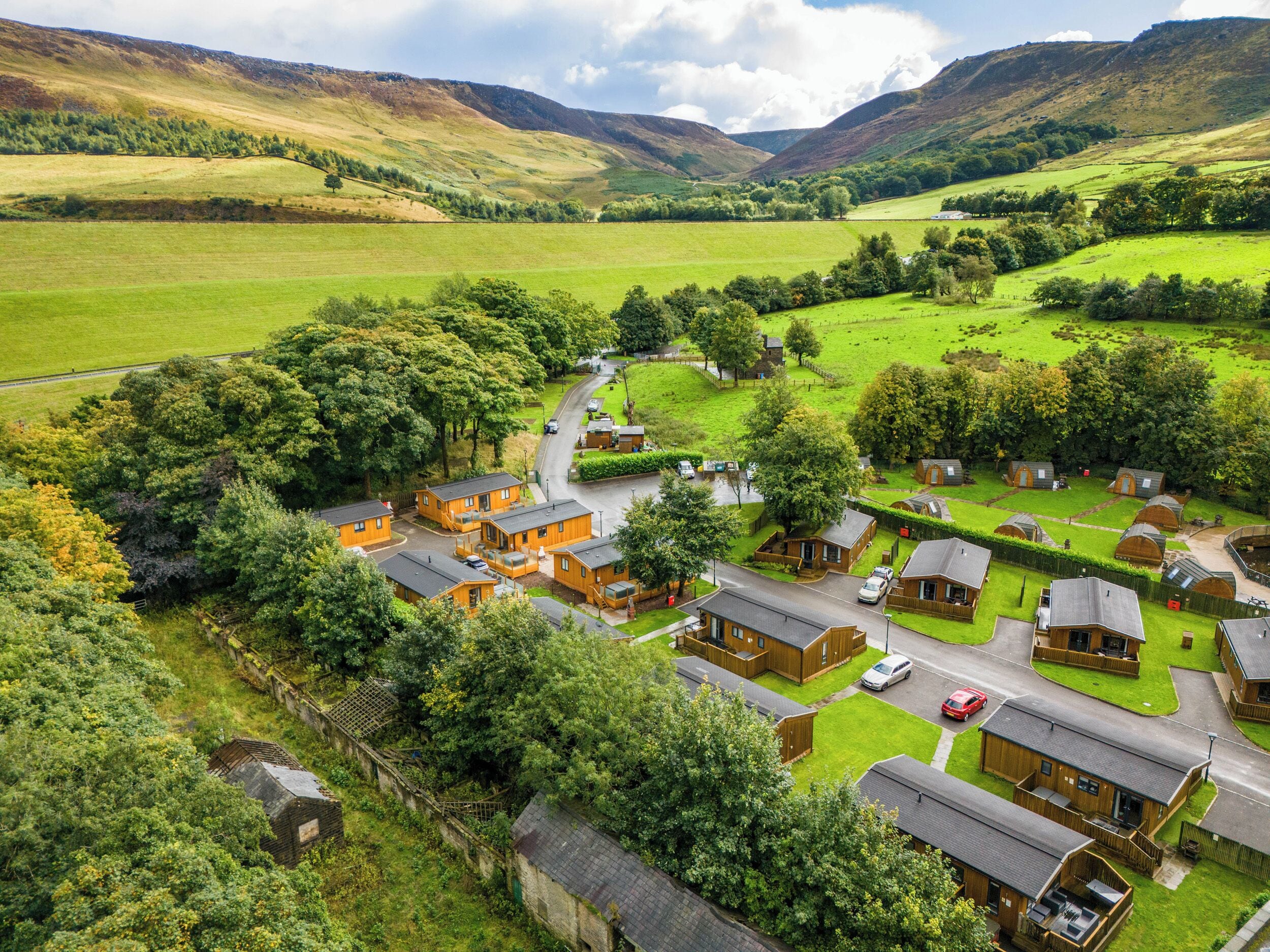 A rural village with traditional wooden houses, a winding road, and surrounding green fields.