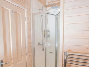 Una cabina doccia in vetro con soffione a mano e rubinetto a parete.