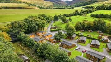 A rural village with traditional wooden houses, a winding road, and surrounding green fields.