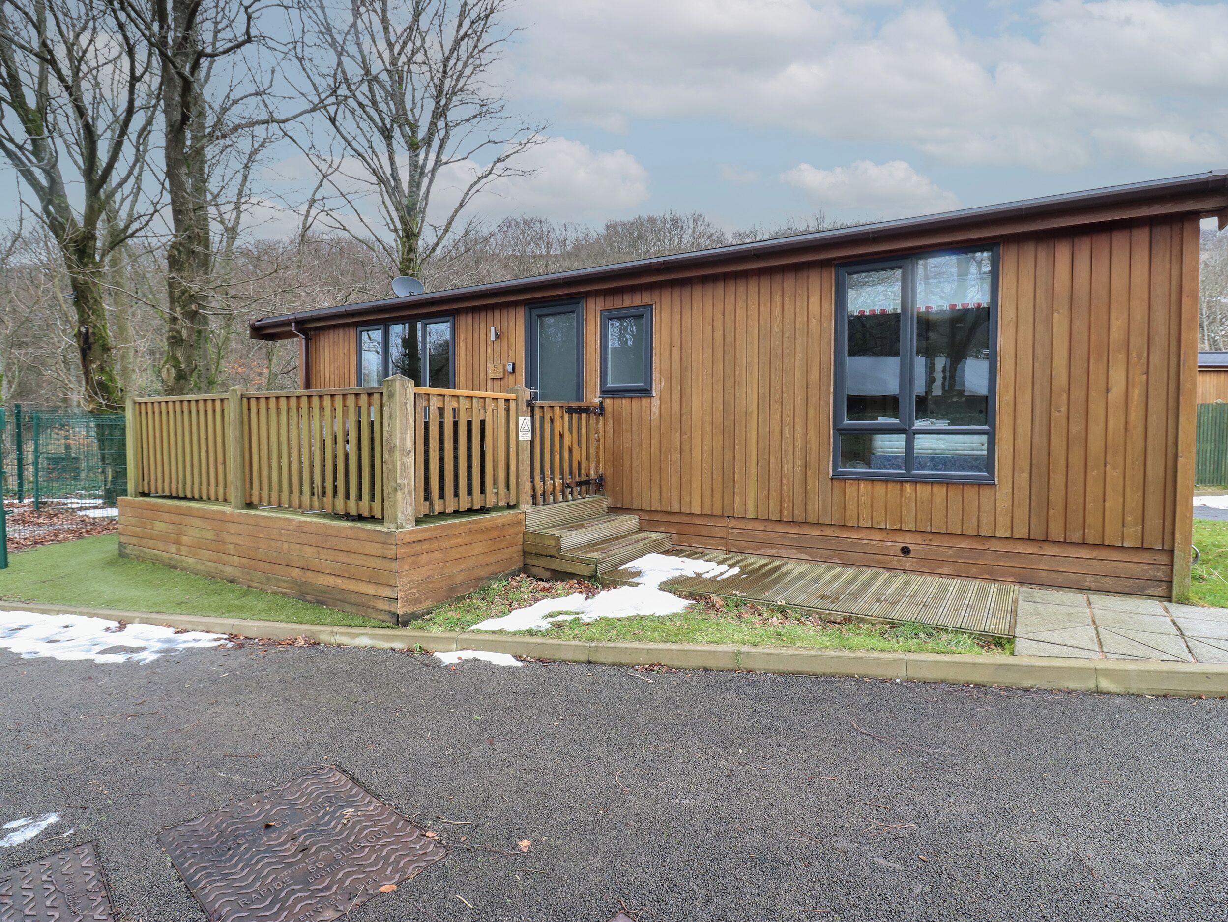 A wooden cabin with a deck, a small porch, and a large window.
