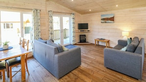 A spacious living area with a sofa set, a television, and a fireplace. - Dovestone Luxury Lodges - pet Free (Oldham)
