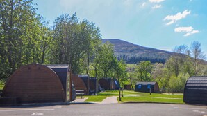 A row of wooden cabins with a mountain in the background. - Dovestone Luxury Lodges - pet Free (Oldham)