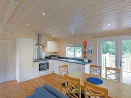 A modern kitchen with white cabinets, a gas stove, and a microwave. There is a dining area with a wooden table and chairs.