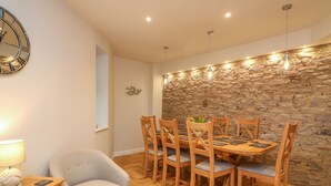 Un comedor con pared de piedra, mesa de madera y sillas.