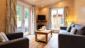 L’intérieur d’un chalet confortable, avec des murs en bois, un canapé, une table et un téléviseur.