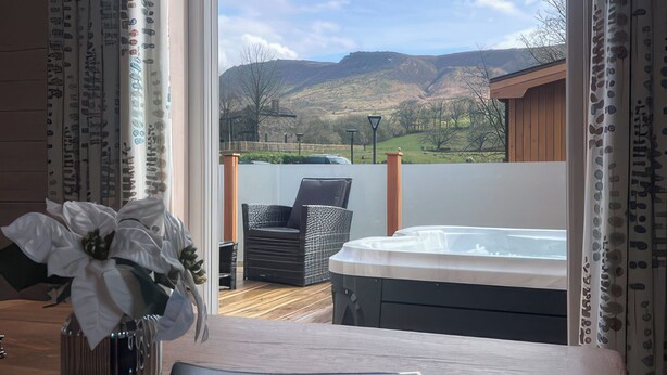 Un balcon avec un jacuzzi, des fauteuils en osier et une vue sur les collines.