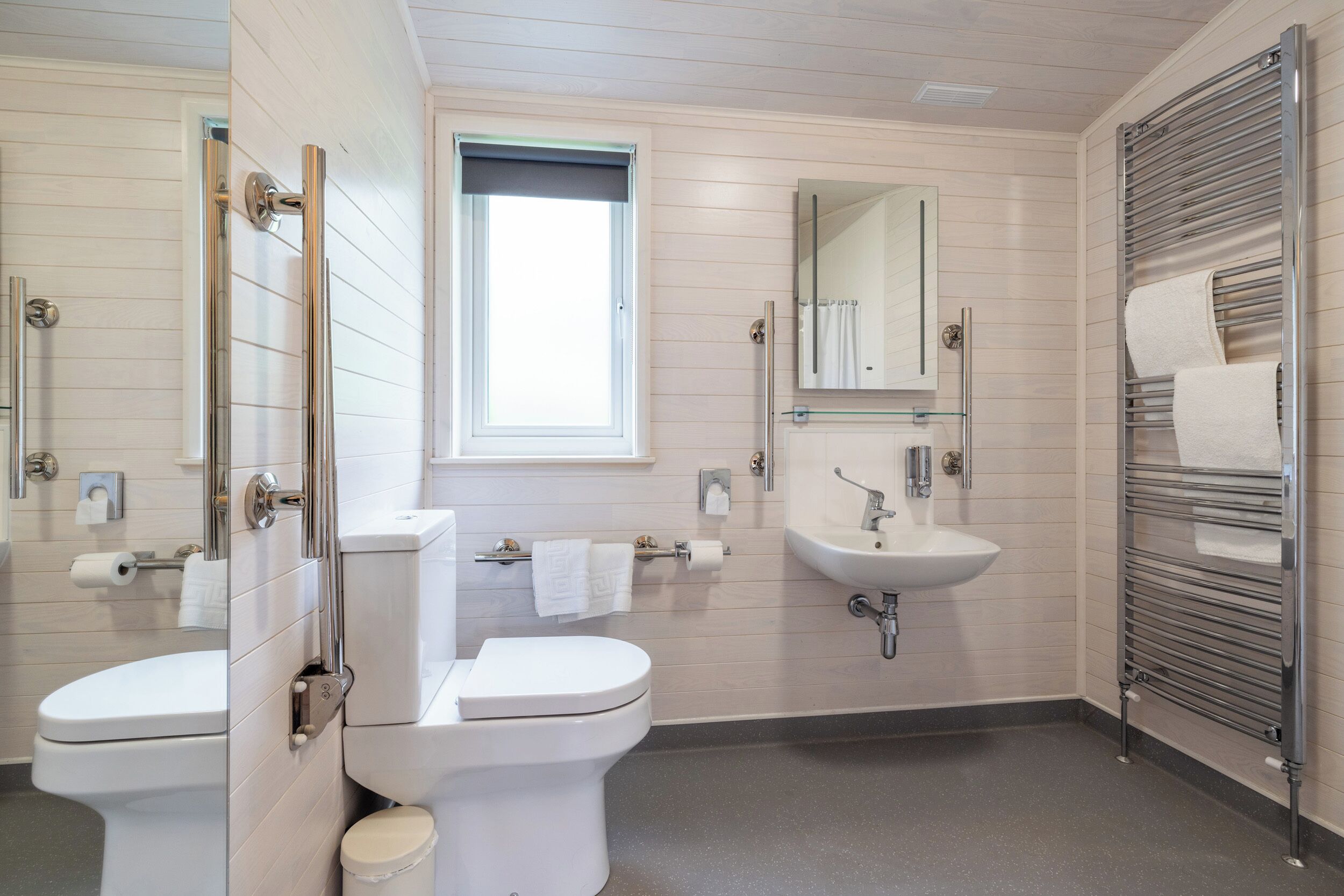 A modern bathroom with two toilets, a sink, and a mirror.