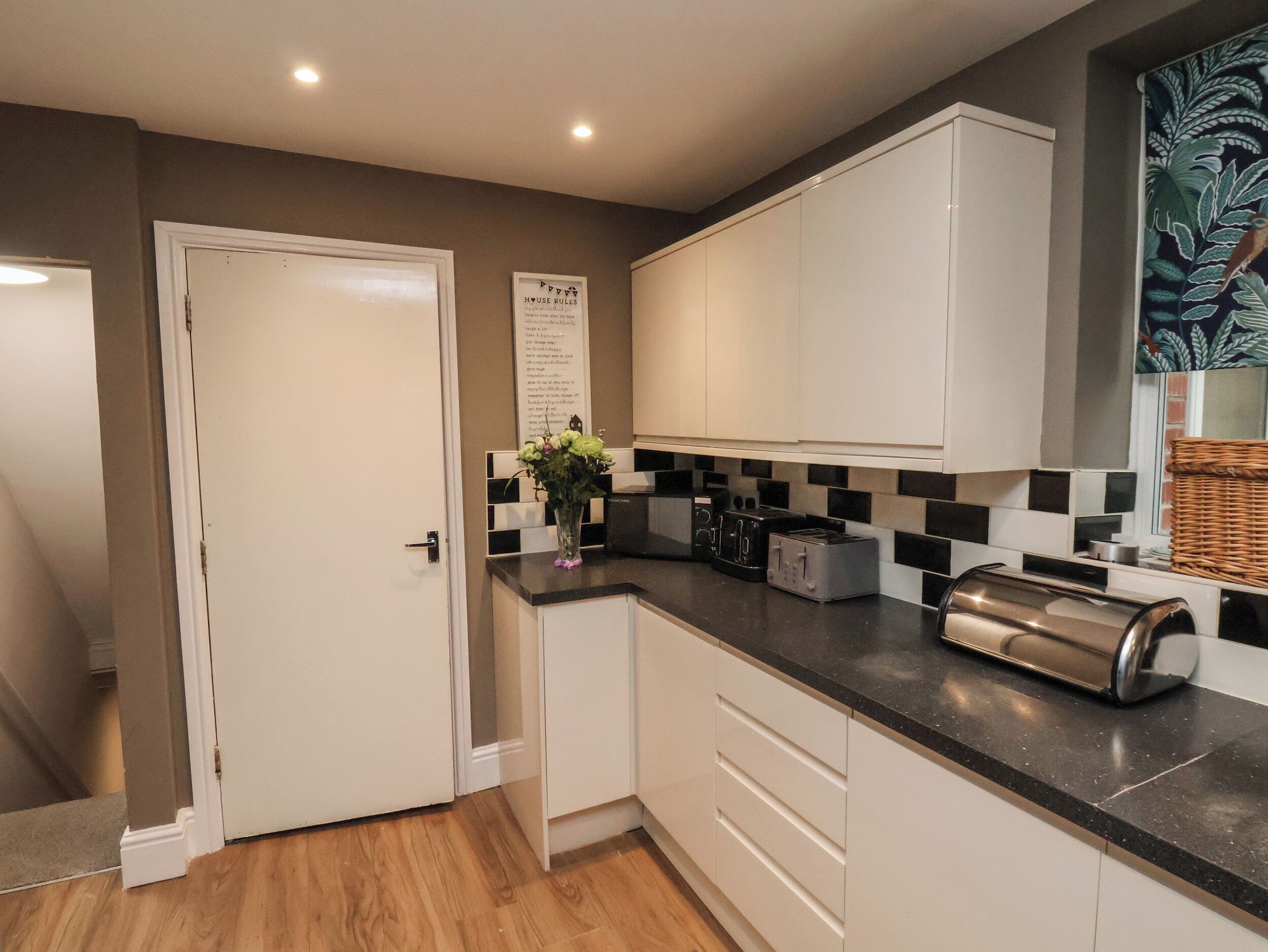 A modern kitchen with white cabinets, a black countertop, and a toaster.
