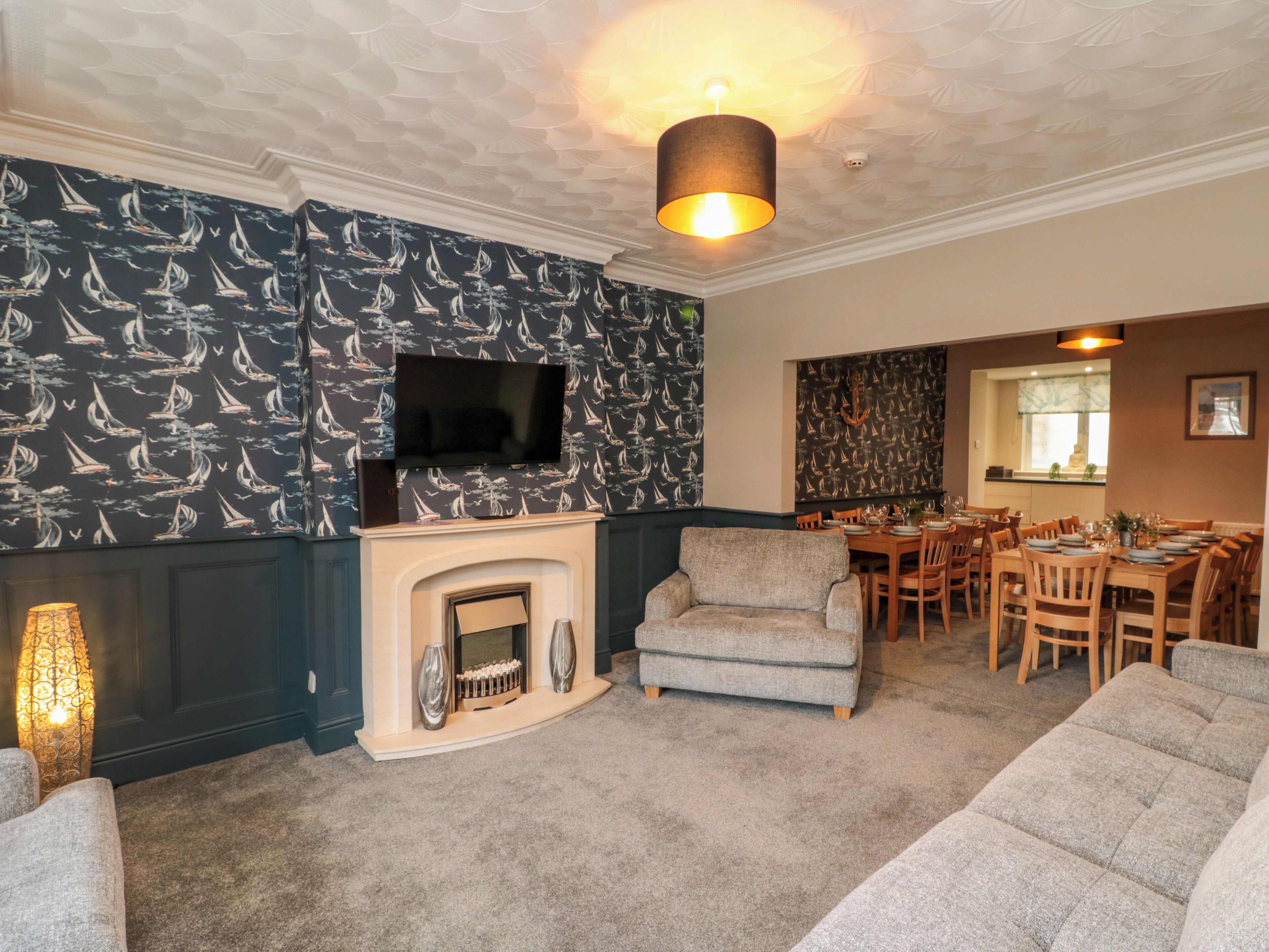 A living room with a fireplace, a television mounted on the wall, and a dining area with wooden furniture.
