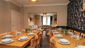 A dining area with a long wooden table set for a meal, flanked by chairs. - Sail Lodge (Scarborough)