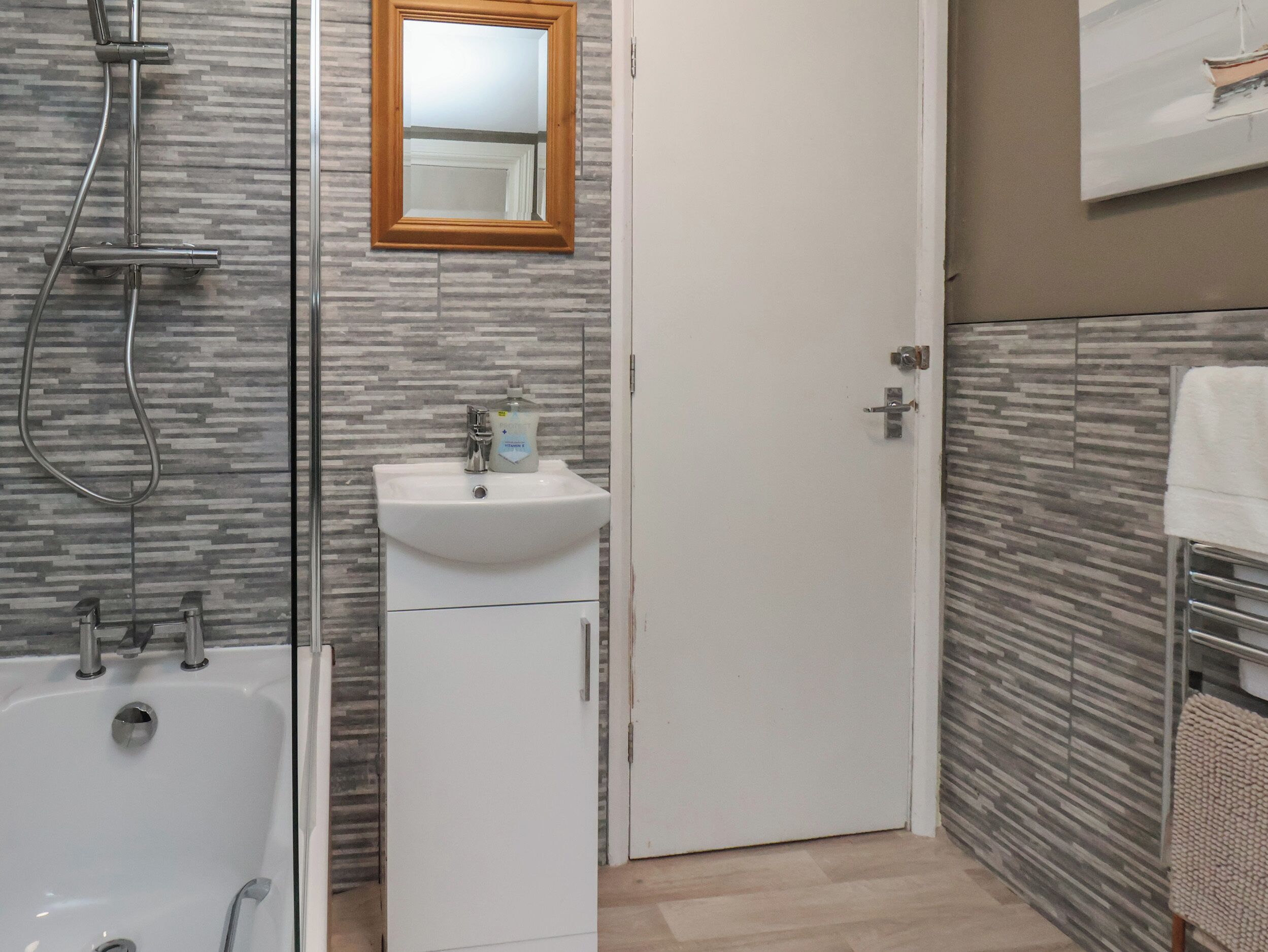 A bathroom with a shower, sink, and mirror.
