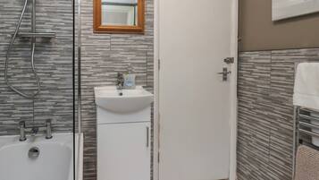 A bathroom with a shower, sink, and mirror.